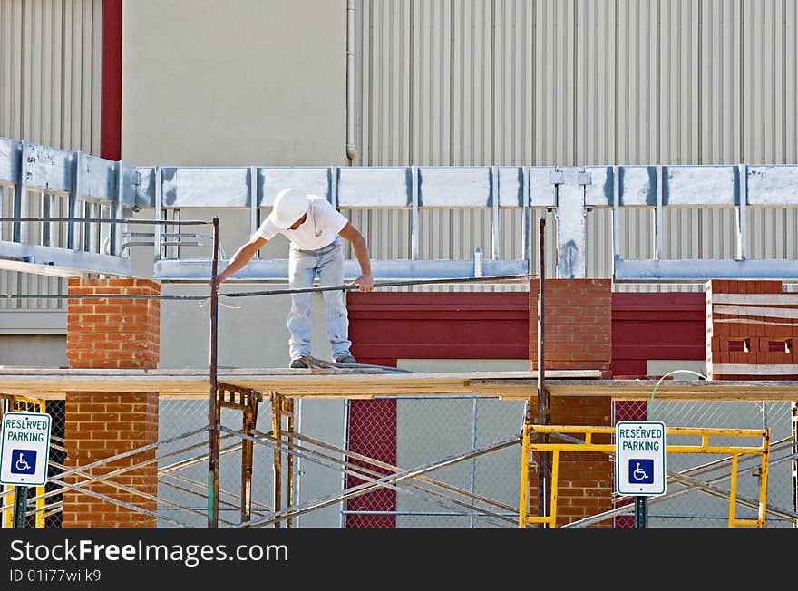 Consruction worker setting up scaffolding at construction site.