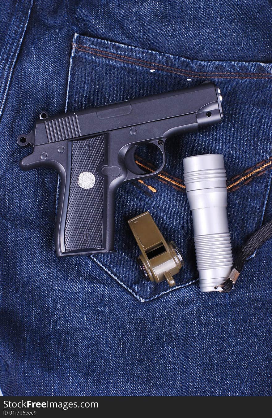 Pistol,flashlight and whistle on cloth of jean