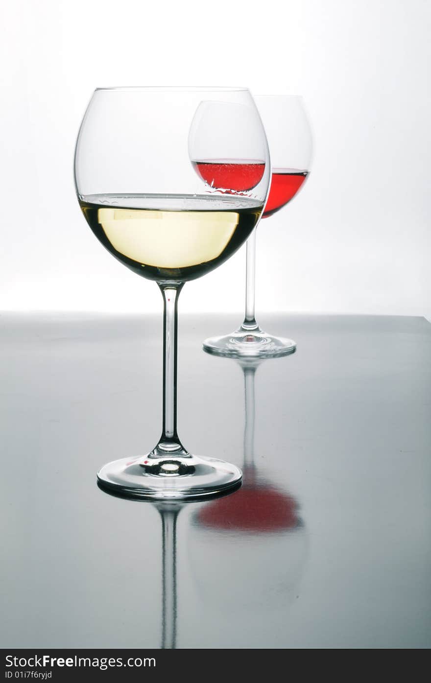 Two glasses of red and white wine on grey isolated on white with reflection