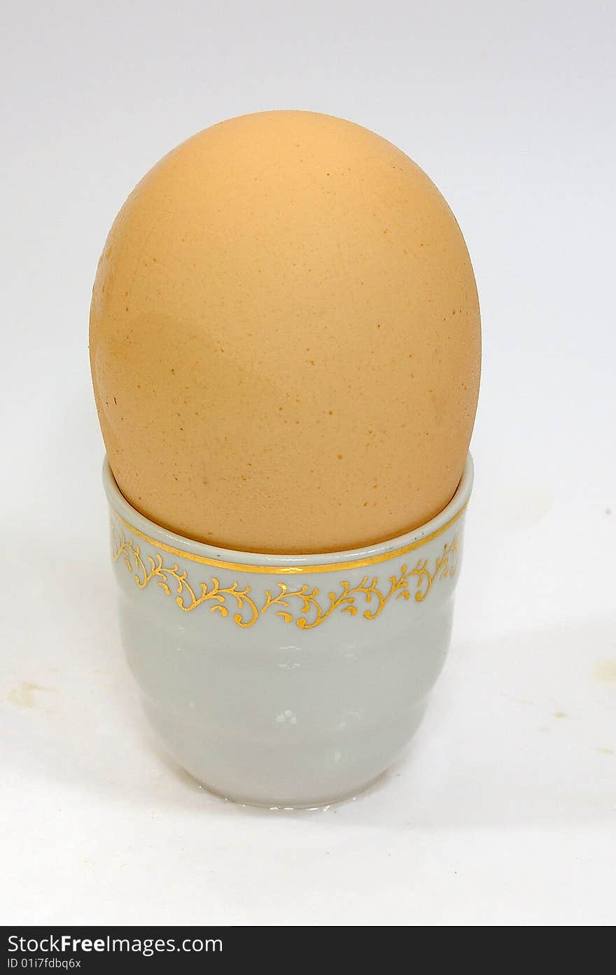 Egg of the hen dietetic yellow on porcelain stand and white background