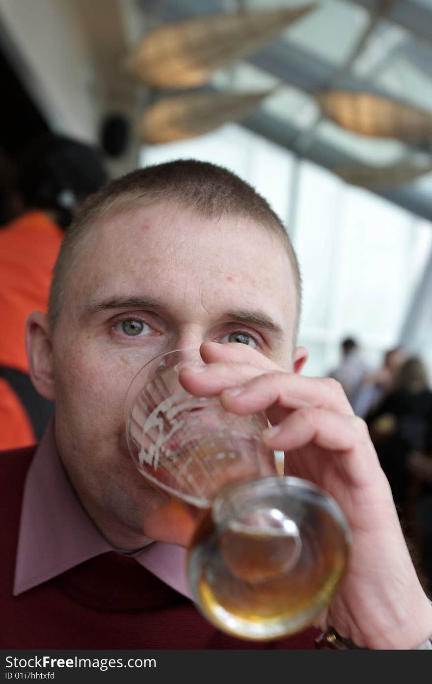 The man drinks a beer in a restaurant. The man drinks a beer in a restaurant