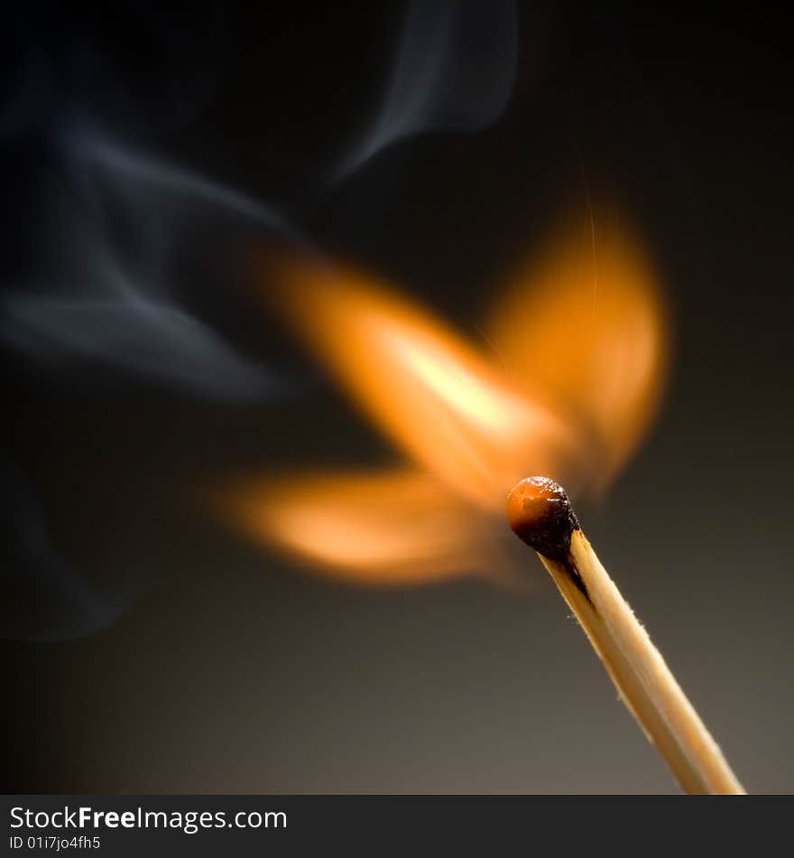 Burning match on black background