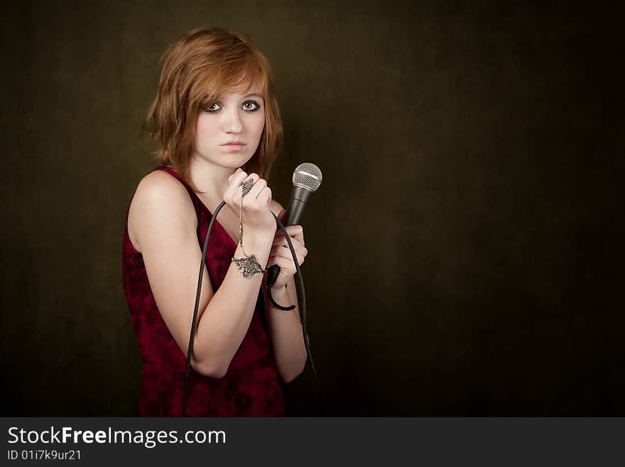 Pretty young girl with red hair on a green background with microphone. Pretty young girl with red hair on a green background with microphone