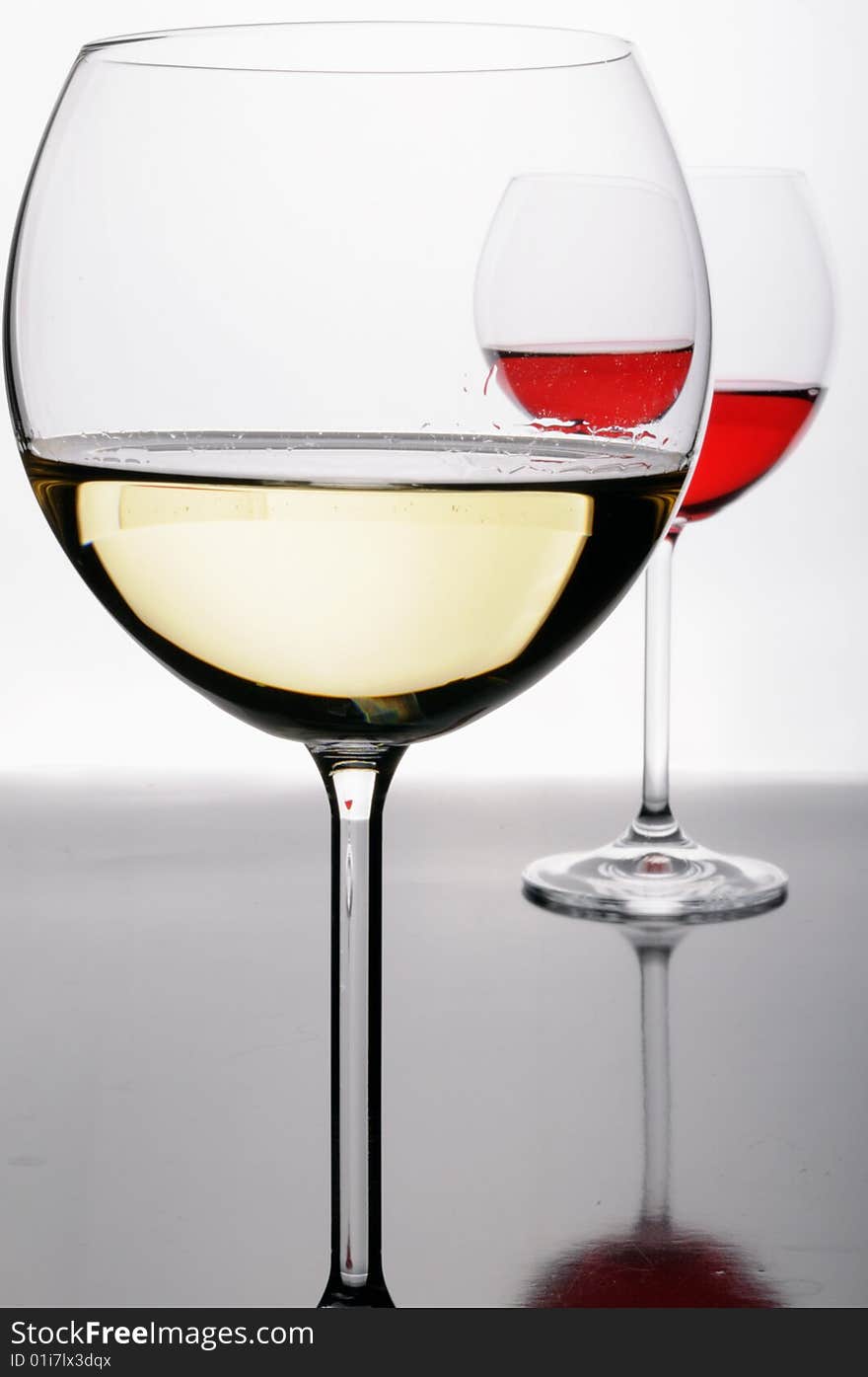 Two glasses of red and white wine on grey isolated on white with reflection