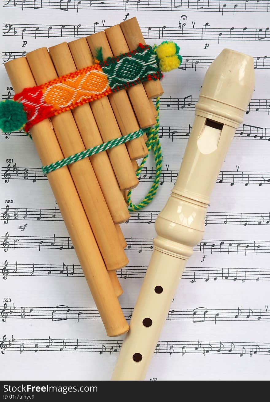 The Mexican pipe with a traditional ornament and a beige flute lay on the partita. The Mexican pipe with a traditional ornament and a beige flute lay on the partita