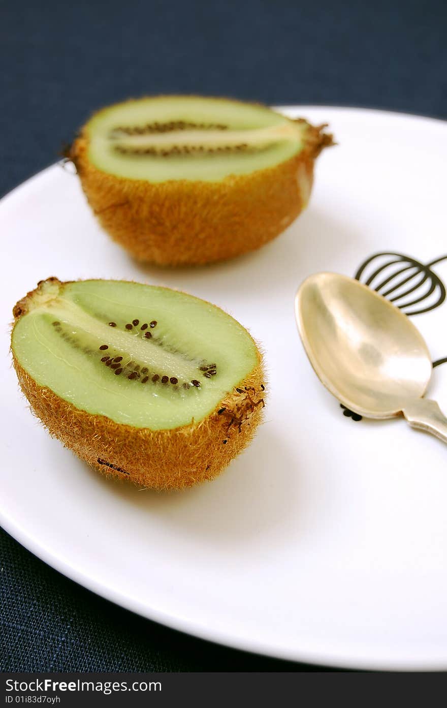 Two half kiwifruit on the white dessert-plate view from one side.