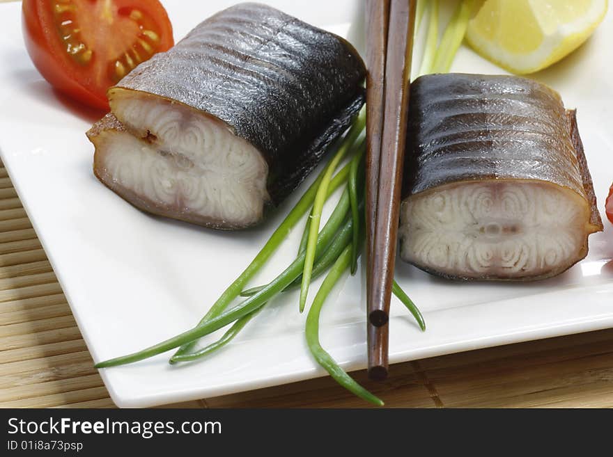 Pieces of smoked eel on a plate with garnish. Pieces of smoked eel on a plate with garnish