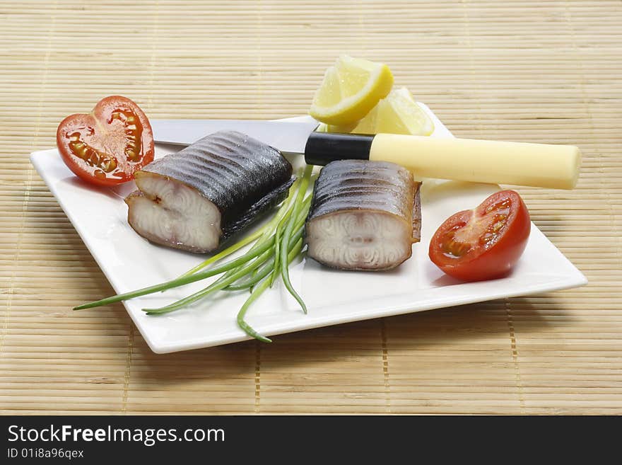 Pieces of smoked eel on a plate with garnish. Pieces of smoked eel on a plate with garnish