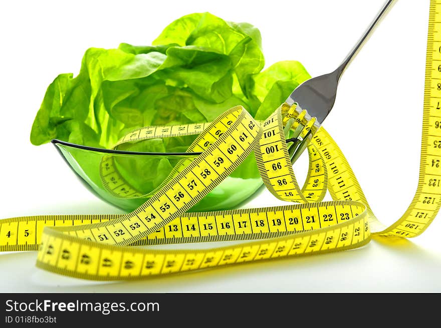 Green salad in bowl a fork and a tape measure. Green salad in bowl a fork and a tape measure