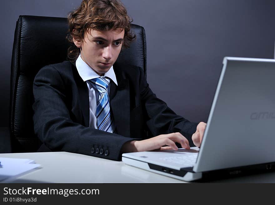 Young businessman at desk using computer laptop. Young businessman at desk using computer laptop