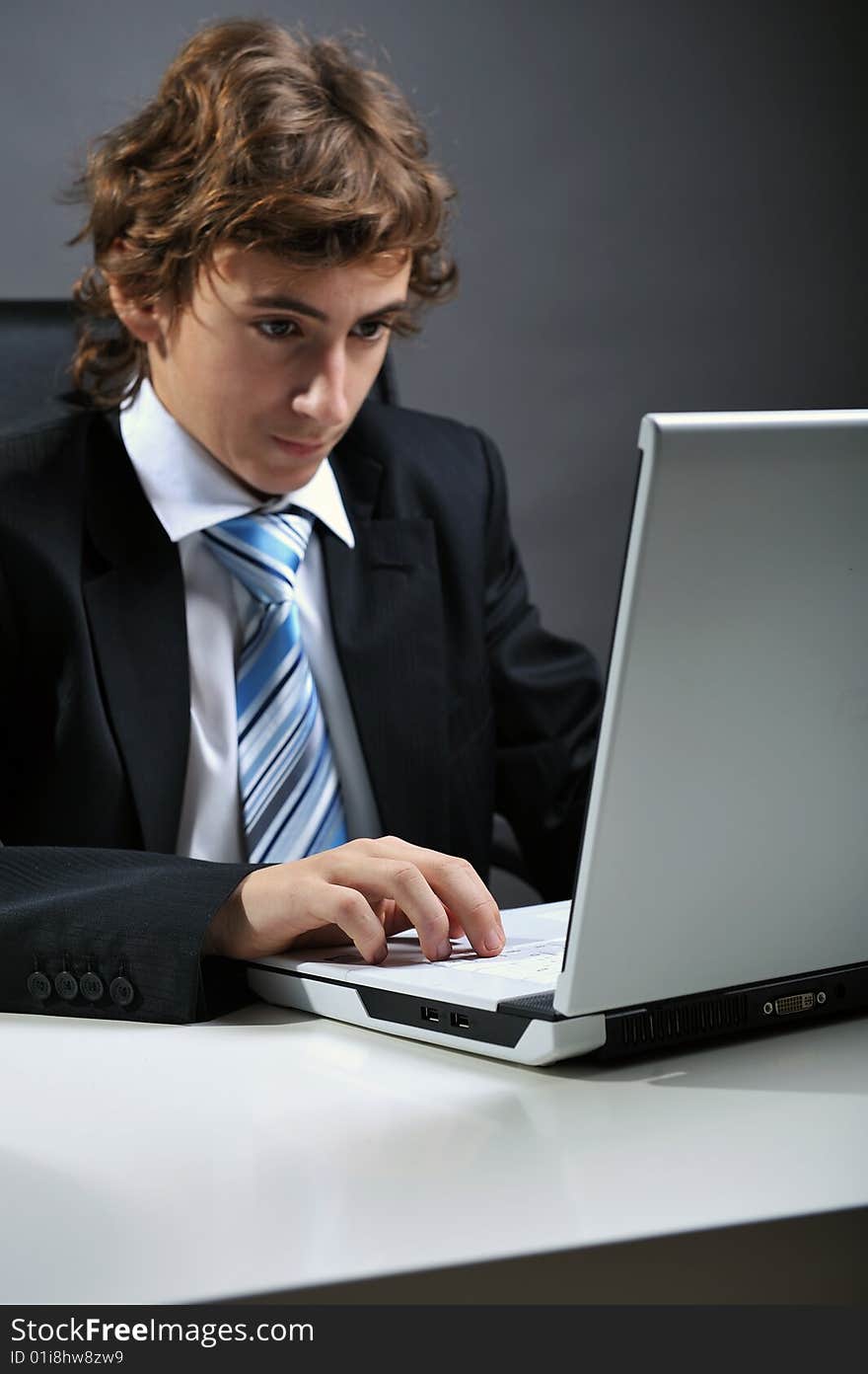 Young businessman at desk using computer laptop. Young businessman at desk using computer laptop