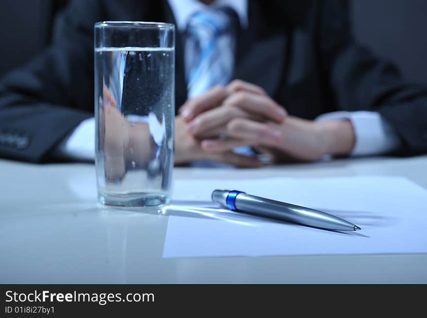 Desk detail with blank paper a pen and businessman hands. Desk detail with blank paper a pen and businessman hands