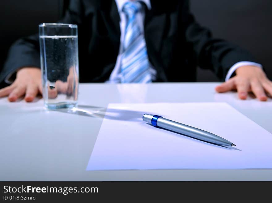 Desk detail with blank paper a pen and businessman hands. Desk detail with blank paper a pen and businessman hands