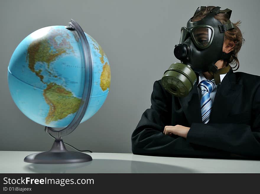 Businessman with gas mask on face looking at earth globe. Businessman with gas mask on face looking at earth globe