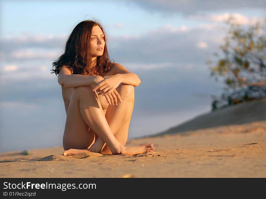 The girl sitting on the sand and looking at the sunset. The girl sitting on the sand and looking at the sunset