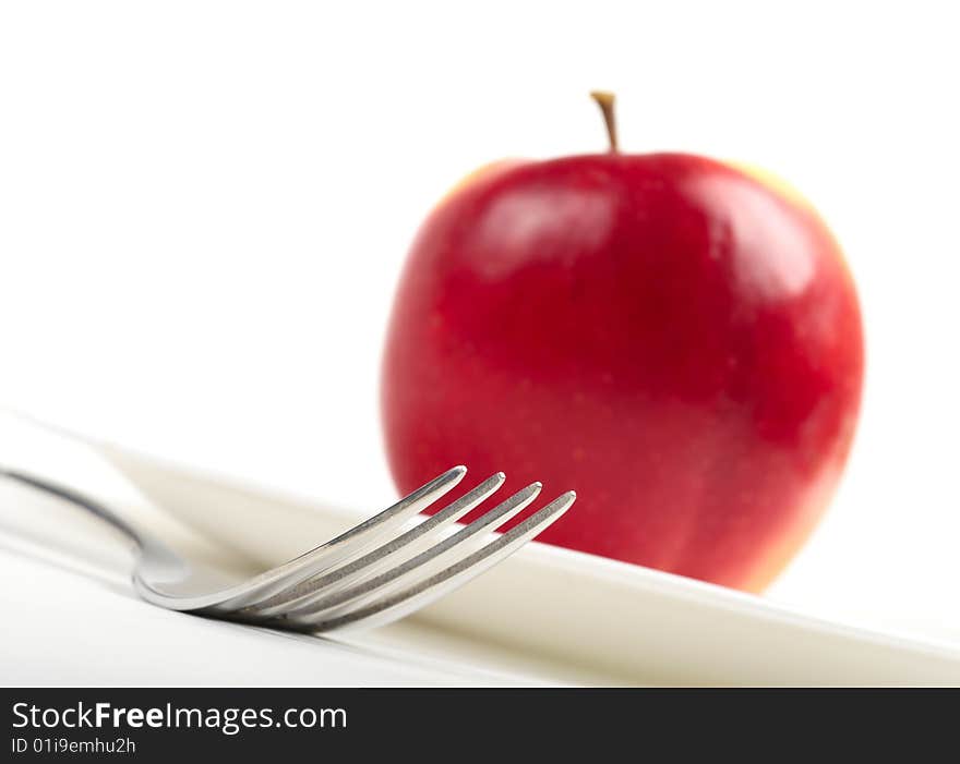 Utensils and red apple on white background