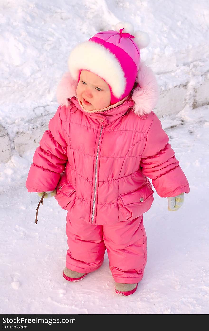 Pretty little girl in winter outerwear with branch on the snow. Pretty little girl in winter outerwear with branch on the snow.