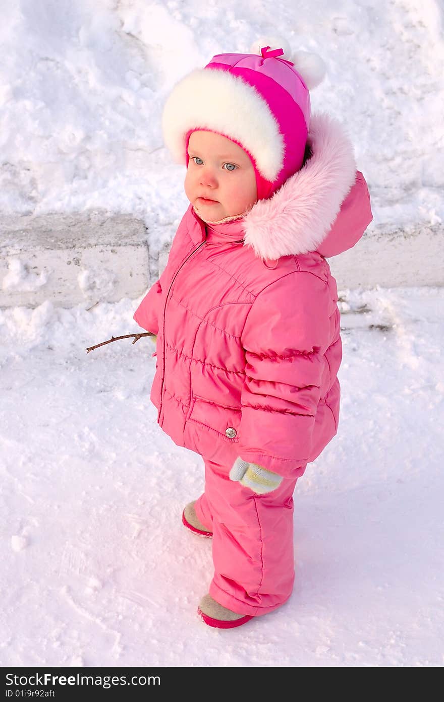 Pretty little girl in winter outerwear with branch on the snow. Pretty little girl in winter outerwear with branch on the snow.