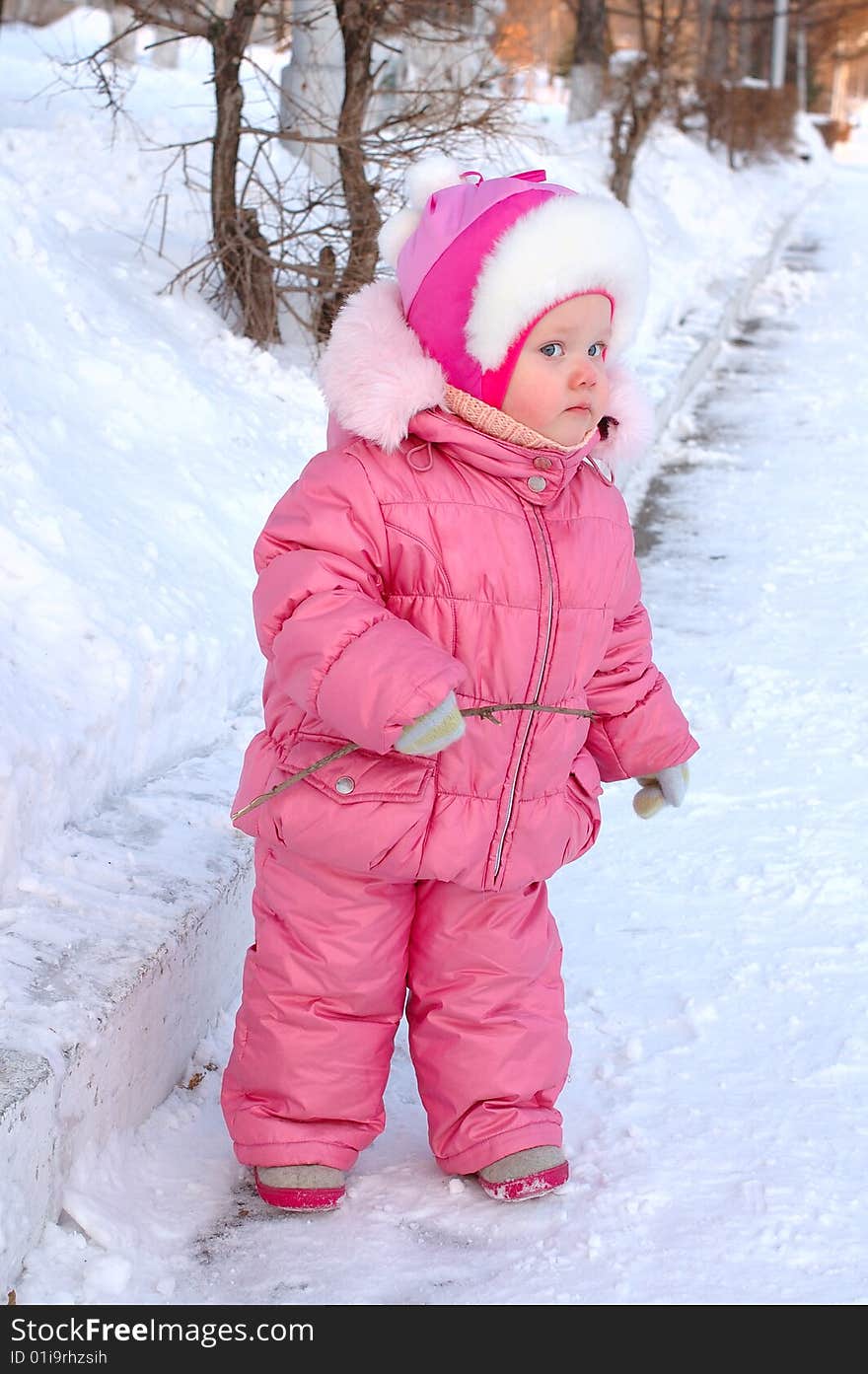 Pretty little girl in winter outerwear with branch on the snow. Pretty little girl in winter outerwear with branch on the snow.