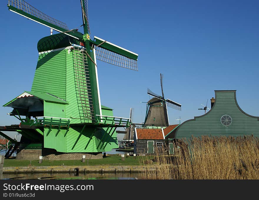 Typical view in the Zaansche Schans in the Netherlands where you can find a collection of old Dutch Wind mills. This windmill named
 “De Kat”  is Paint Mill, for grinding pigments for the manufacturing of paint and the green colored Wood Sawing Mill Paltrok or post mill named 'De Gekroonde Poelenburg' (detail) , Zaanse homes, decorated with typical Zaans green colored paint. Typical view in the Zaansche Schans in the Netherlands where you can find a collection of old Dutch Wind mills. This windmill named
 “De Kat”  is Paint Mill, for grinding pigments for the manufacturing of paint and the green colored Wood Sawing Mill Paltrok or post mill named 'De Gekroonde Poelenburg' (detail) , Zaanse homes, decorated with typical Zaans green colored paint.