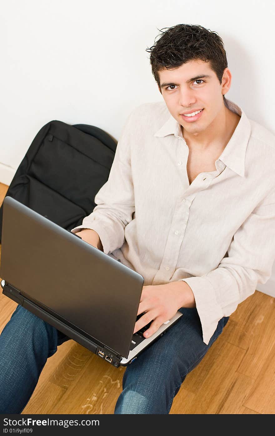 Happy young man working on his laptop with casual clothing and bag. Happy young man working on his laptop with casual clothing and bag