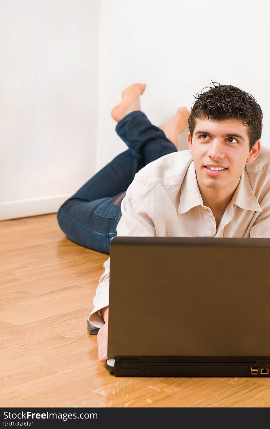 Happy young dreamful man working on his laptop with casual clothing. Happy young dreamful man working on his laptop with casual clothing