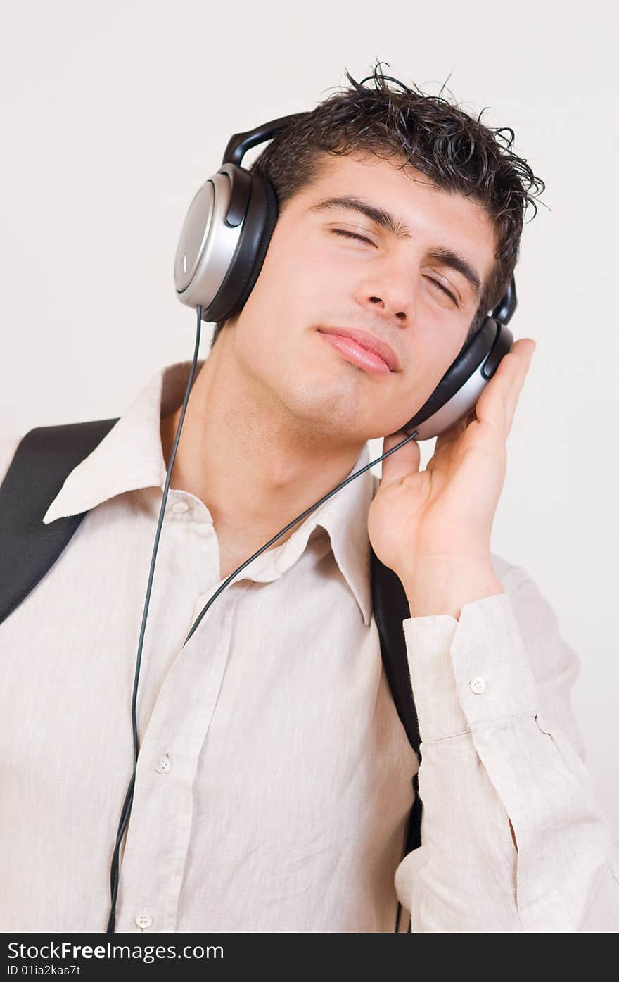 Portrait of young man listening music in headphones with great pleasure and closed eyes.