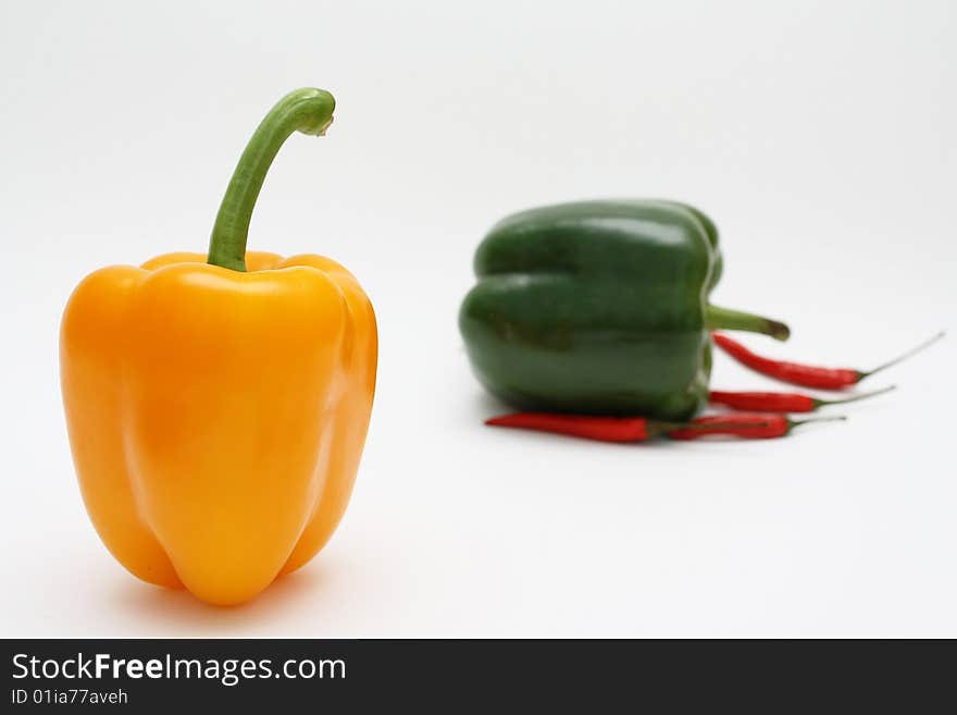 Orange, green and red pepper on white background