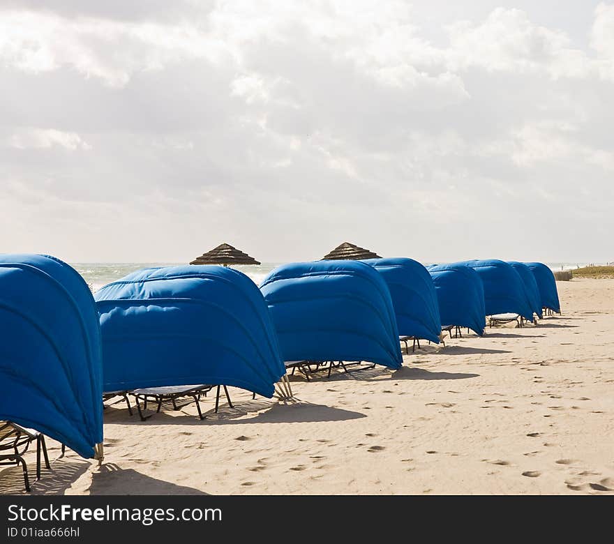 Blue Beach Shelters and Umbrellas on a beach on a cloudy day. Blue Beach Shelters and Umbrellas on a beach on a cloudy day