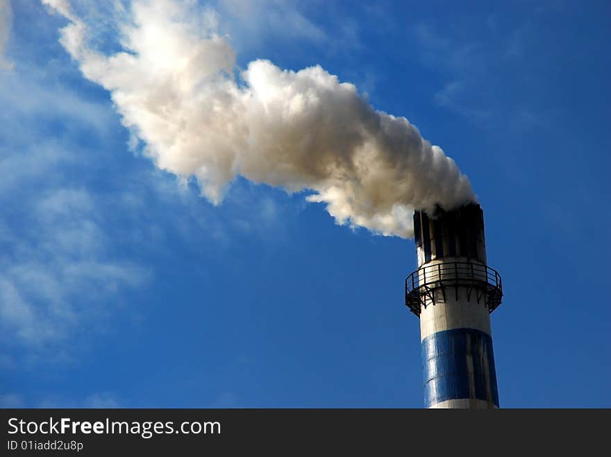 A big chimney was smoking under the blue sky. A big chimney was smoking under the blue sky.