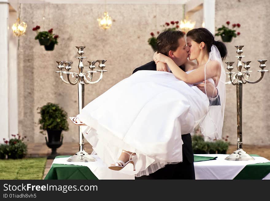 Groom holding bride kissing