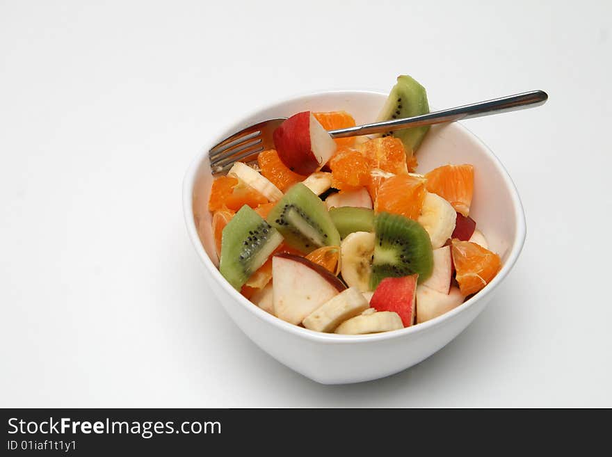 Fruit salad in bowl with fork on the white background
