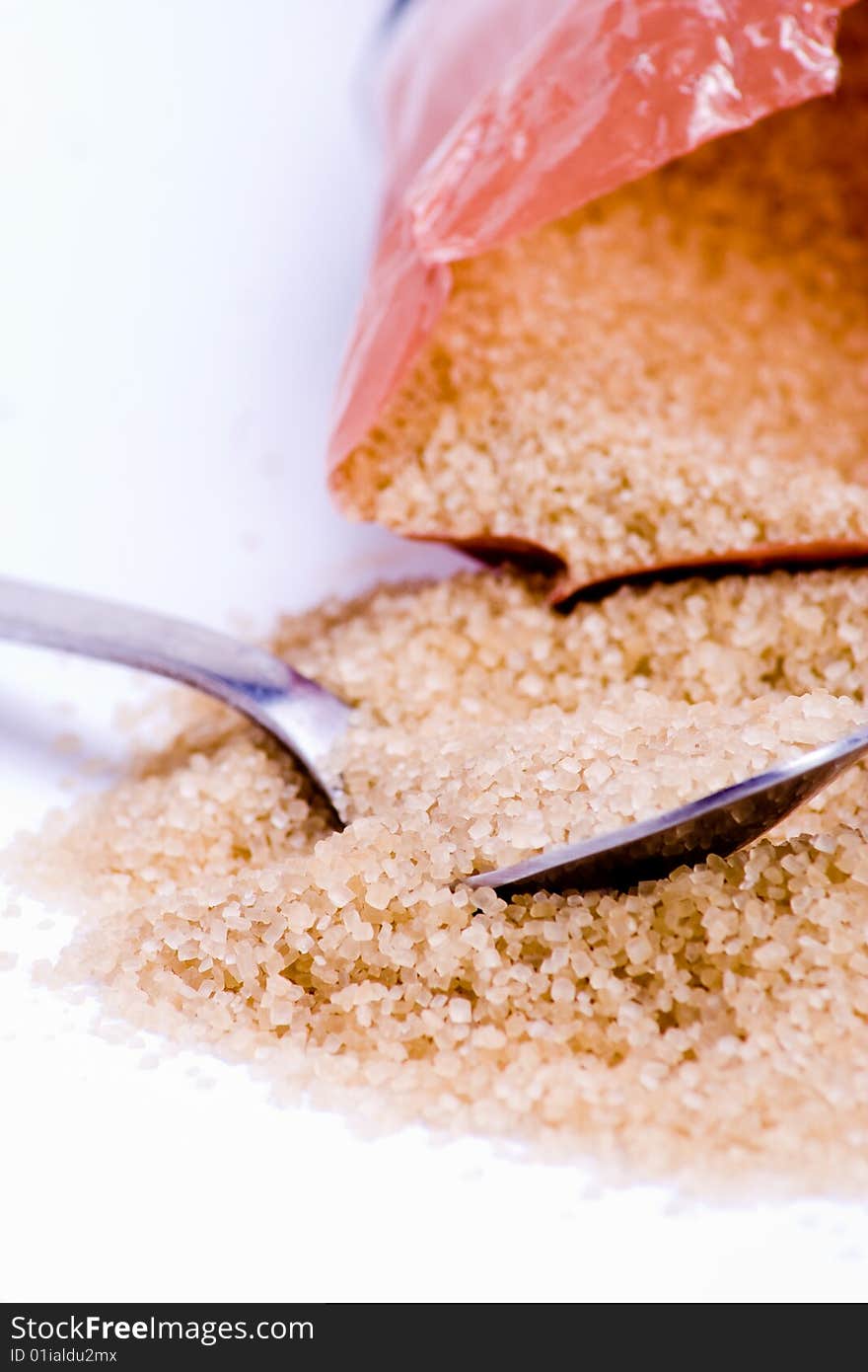 A mound of packaged brown sugar with a spoon. A mound of packaged brown sugar with a spoon