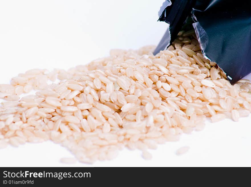 Dried rice spilt from packaging over white. Dried rice spilt from packaging over white