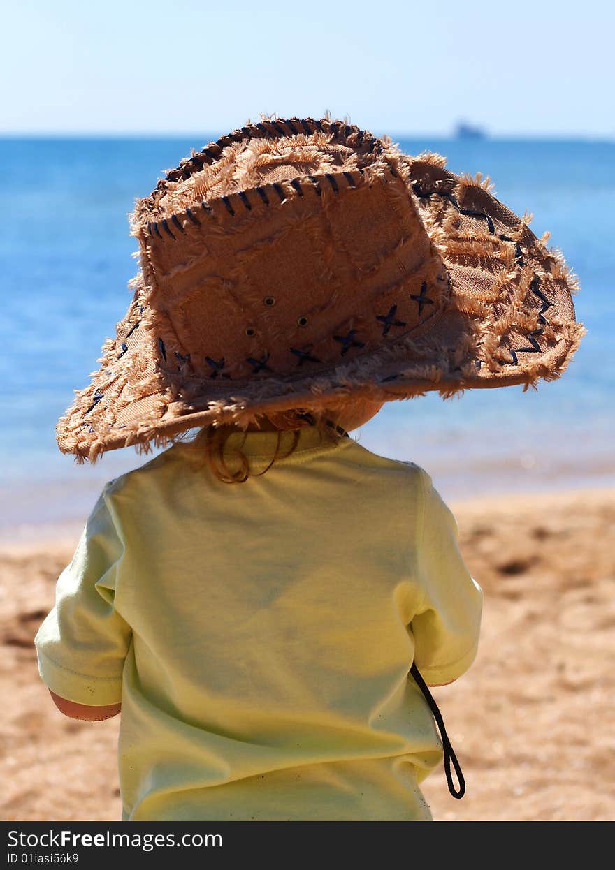 A little girl in a big cowboy hat on the beach. A little girl in a big cowboy hat on the beach