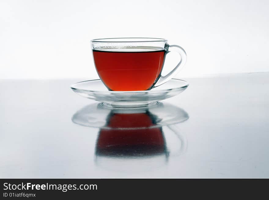 A glass cup of tea on black isolated on white background