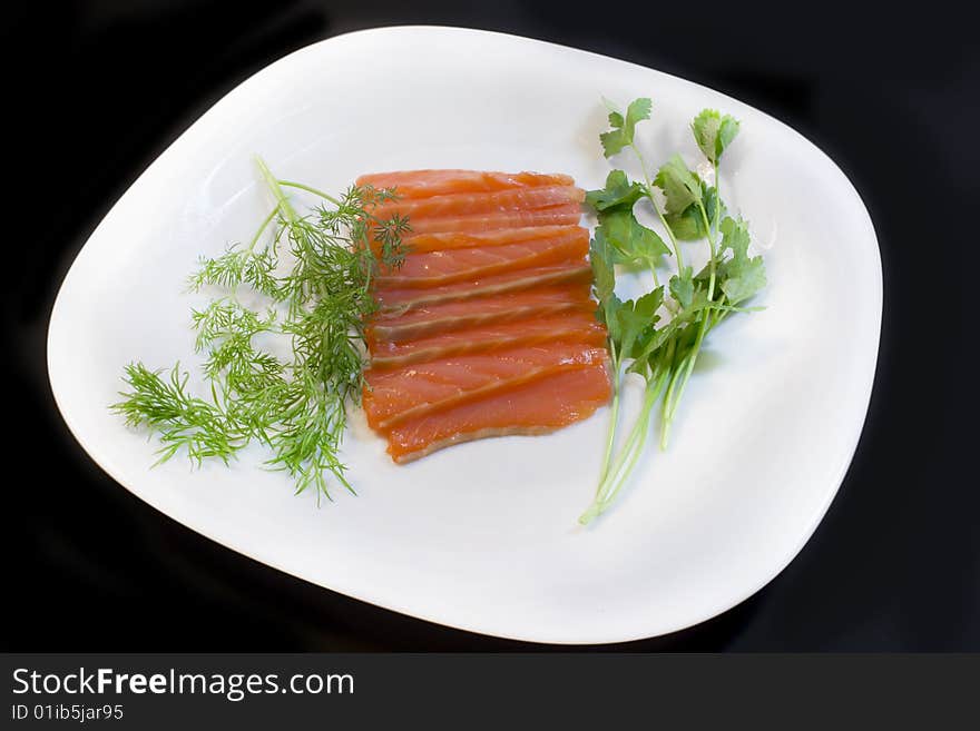 Salmon, fennel and parsley on a plate, a photo close up on a black background. Salmon, fennel and parsley on a plate, a photo close up on a black background.