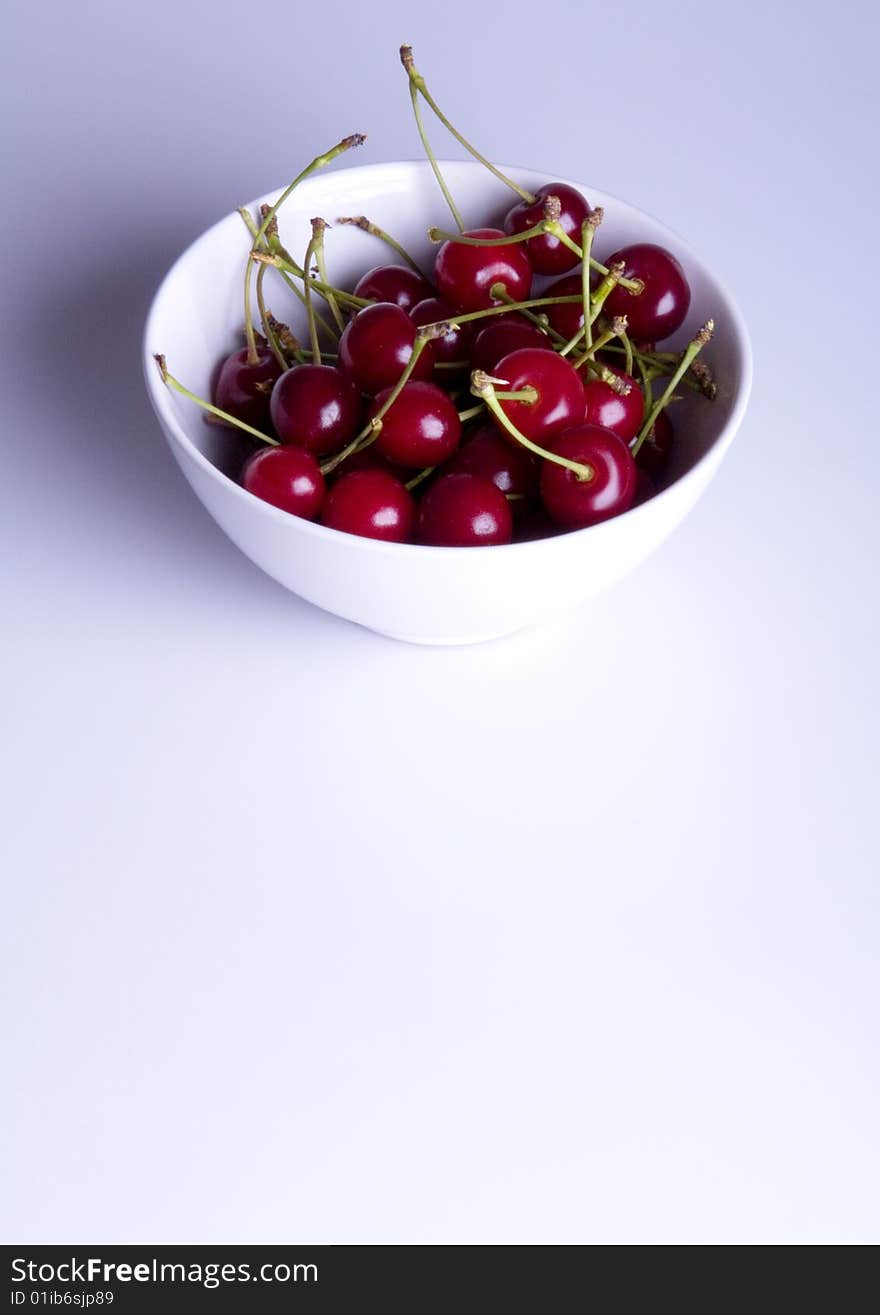 Big red cherries in bowl on white background