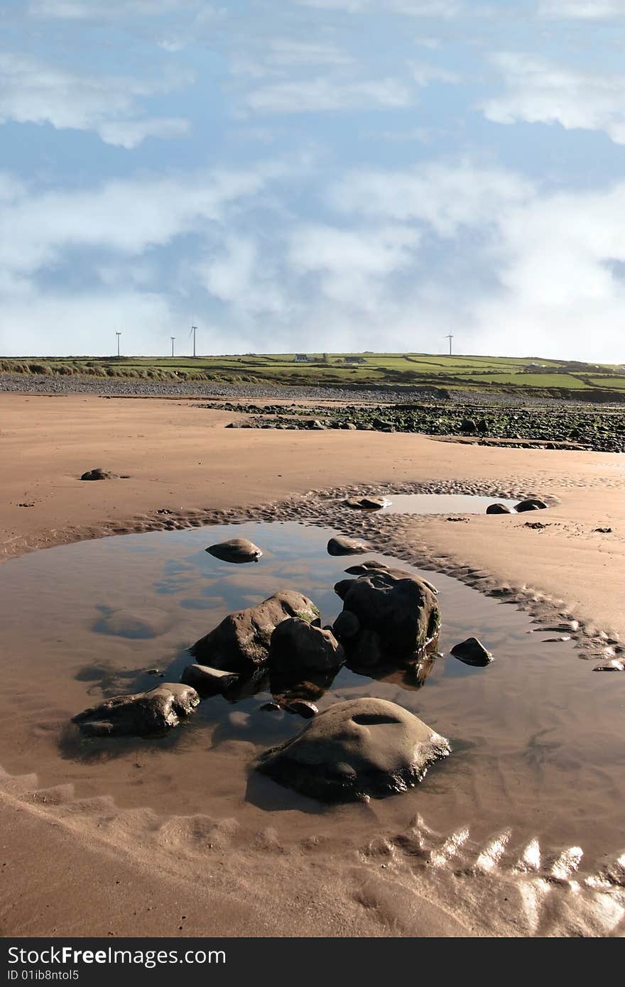 Rock pool on beale beach co kerry ireland on a cold winters morning with turbines in the background. Rock pool on beale beach co kerry ireland on a cold winters morning with turbines in the background