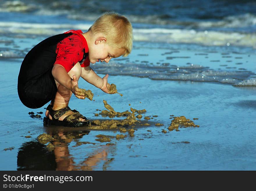 Boy playing in sand at water's edge