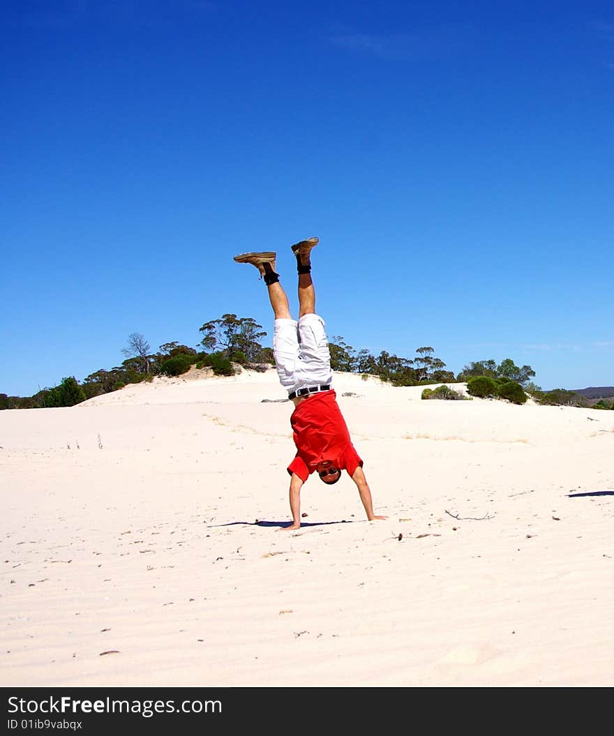 A man doing a handstand in Victoria's Mallee Desert at the 'Snowdrift' Sand Dune (Wyperfeld National Park, Australia). A man doing a handstand in Victoria's Mallee Desert at the 'Snowdrift' Sand Dune (Wyperfeld National Park, Australia).