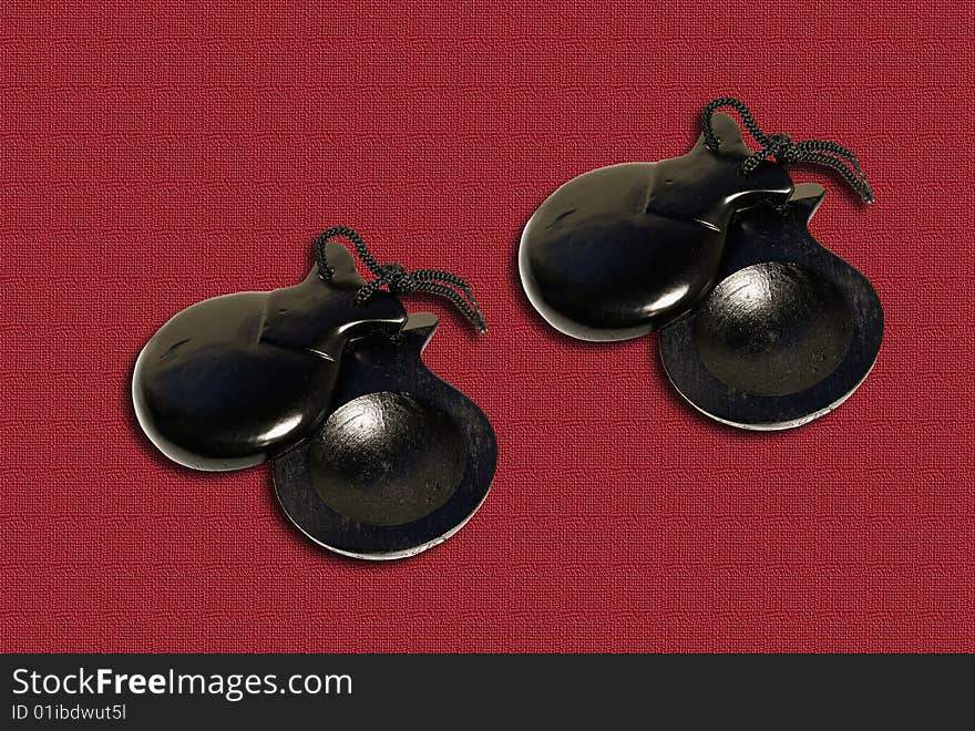 Two pair of castanets on the red textile background.