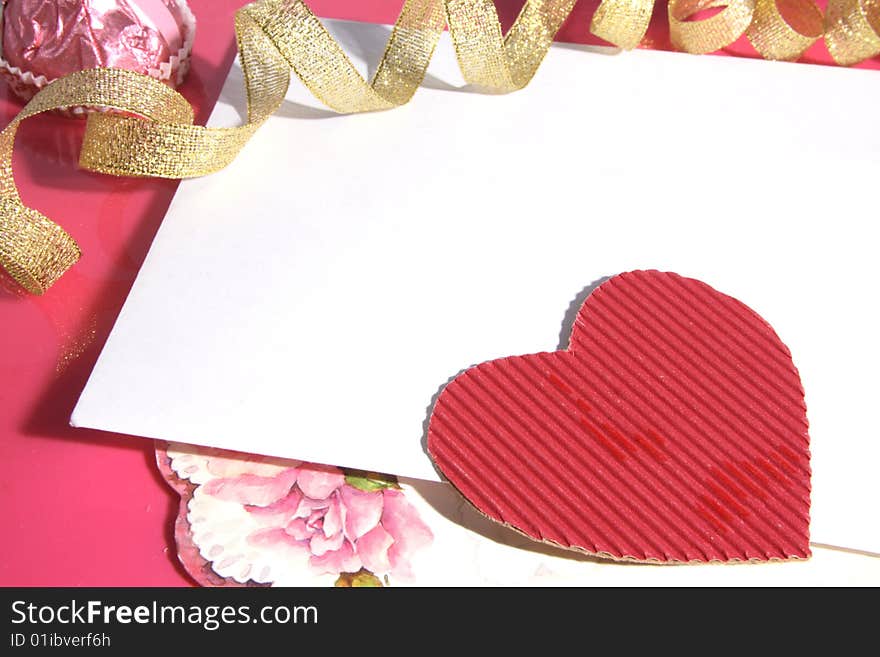 Background with cardboard heart of red color and a gold tape.