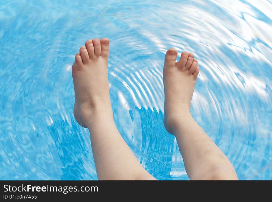 A young kids feet over blue pool water. A young kids feet over blue pool water