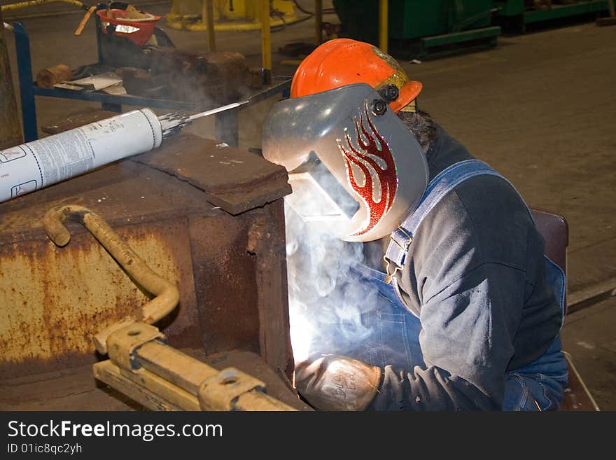 Man welding on railroad car with hard hat and welding shield. Man welding on railroad car with hard hat and welding shield.