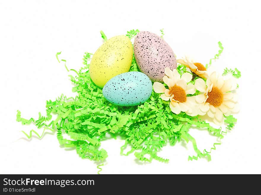 Easter eggs in green paper grass  with three flower isolated on the white. Easter eggs in green paper grass  with three flower isolated on the white