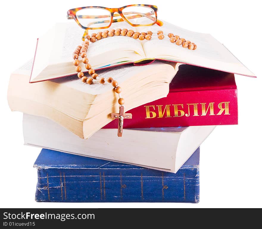 Open Holy Bible lying on stack of old books with glasses, cross and beads. Open Holy Bible lying on stack of old books with glasses, cross and beads