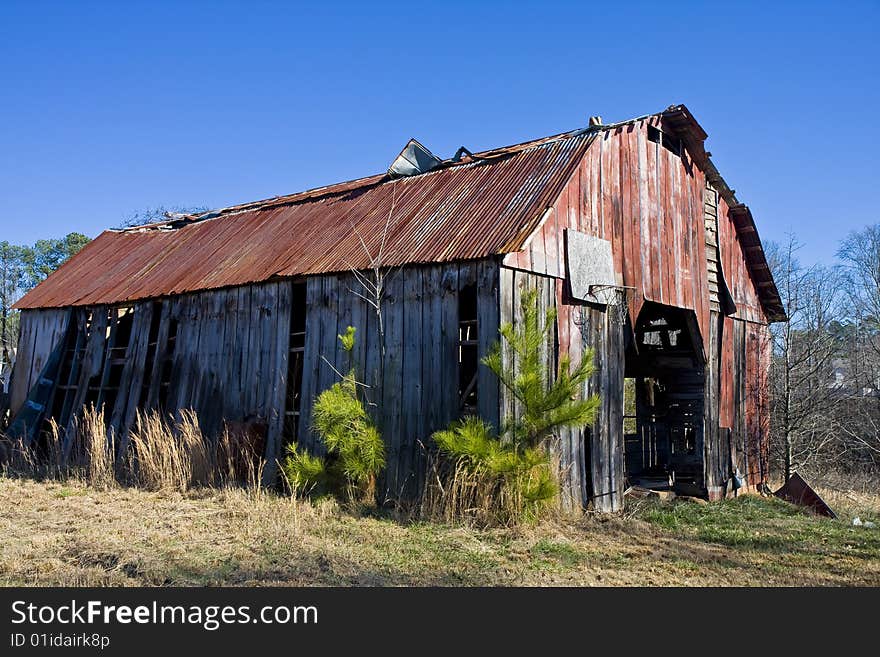 An old barn with a rusty roof in a rural area. An old barn with a rusty roof in a rural area