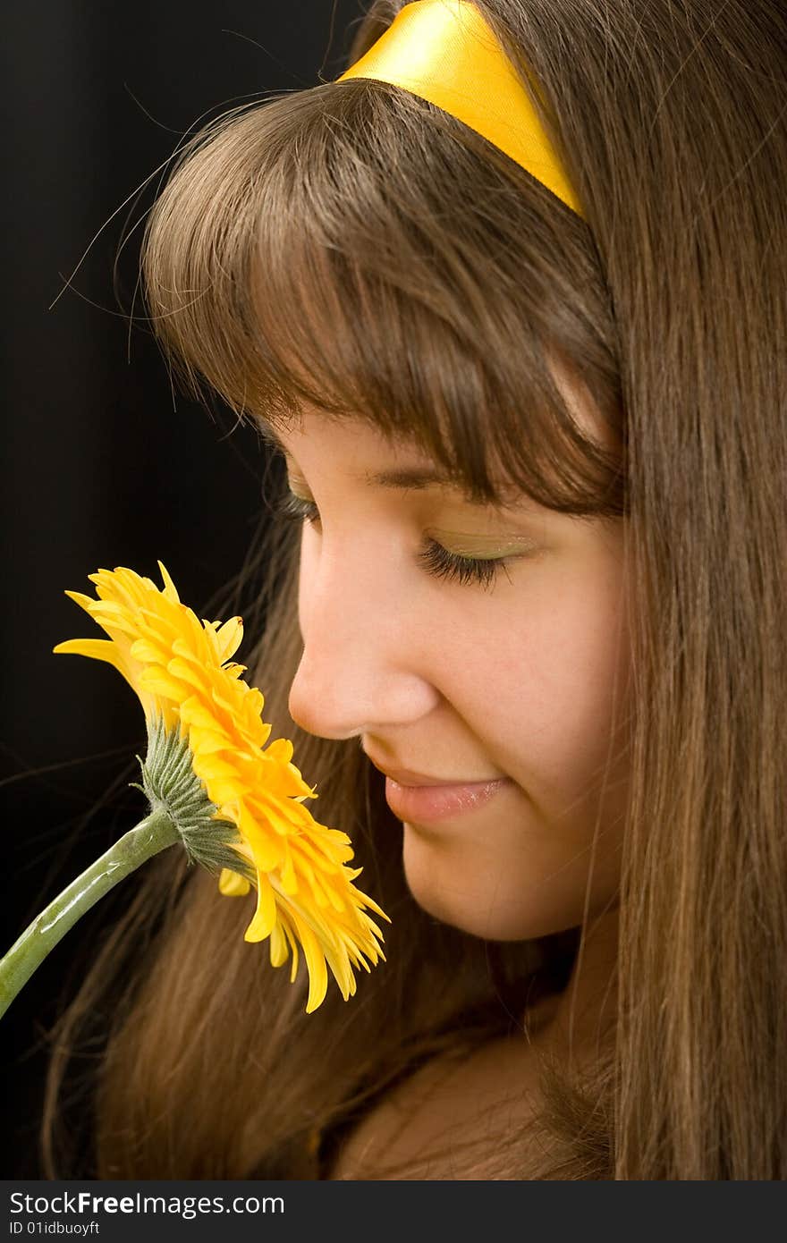 Portrait of beautiful girl with yellow flower on black