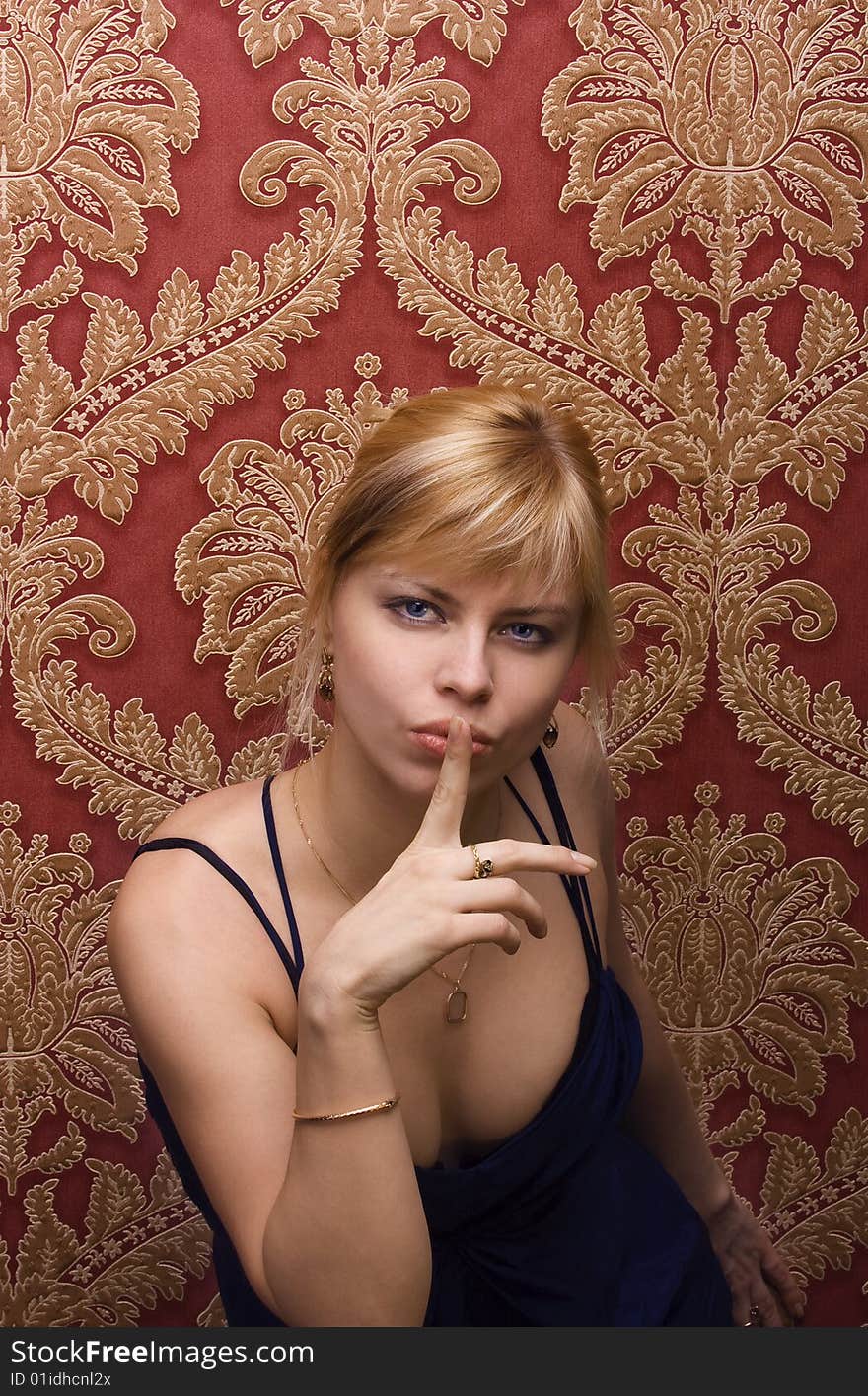 Young beautiful girl blonde on a background a red wall with patterns. Young beautiful girl blonde on a background a red wall with patterns